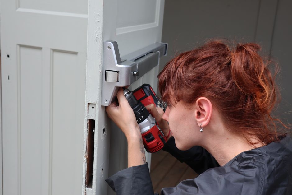 Technician drilling new lock hardware into a door
